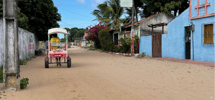 #ParaTodosVerem: Fotografia mostra uma das ruas da vila de Algodoal. Caminho é coberto por areia e tem uma charrete transitando. 