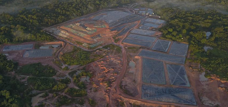 Em Belém, o aterro sanitário continua desafiando gestores municipais da Região Metropolitana. #ParaTodosVerem: Fotografia mostra o lixão de Marituba visto de cima. No centro, temos a área onde o lixo é depositado e, ao redor, a área verde de mata fechada.